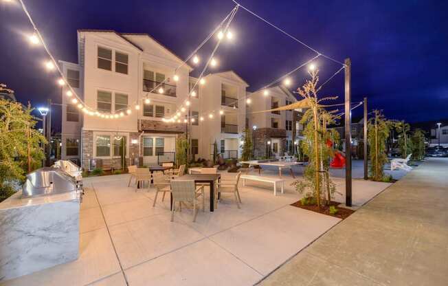BBQ and Outdoor Seating Area at nighttime with white lights strung back and forth across the area at Morgan Ranch Apartments, Morgan Hill, California