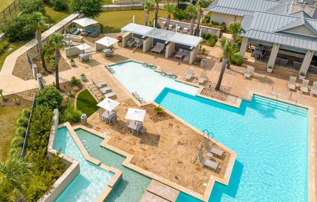 an aerial view of the resort style pool with lounge chairs and tables