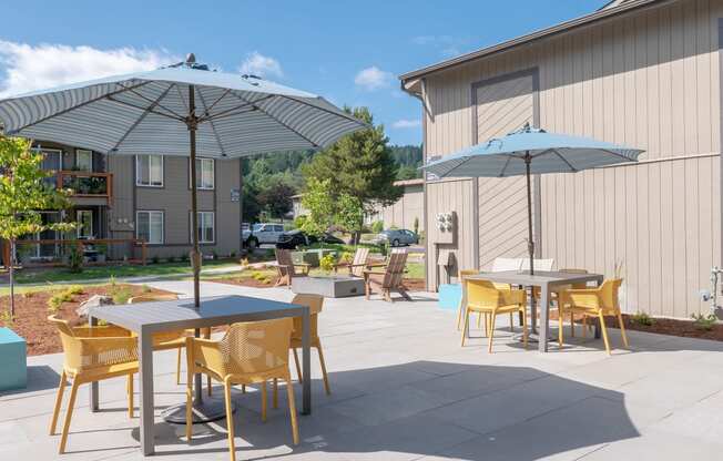 a patio with tables and umbrellas at the whispering winds apartments in pearland, tx