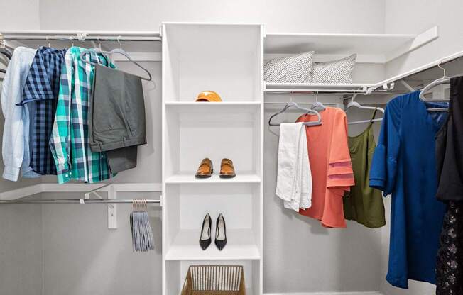 a walk in closet with shelves and clothes and shoes