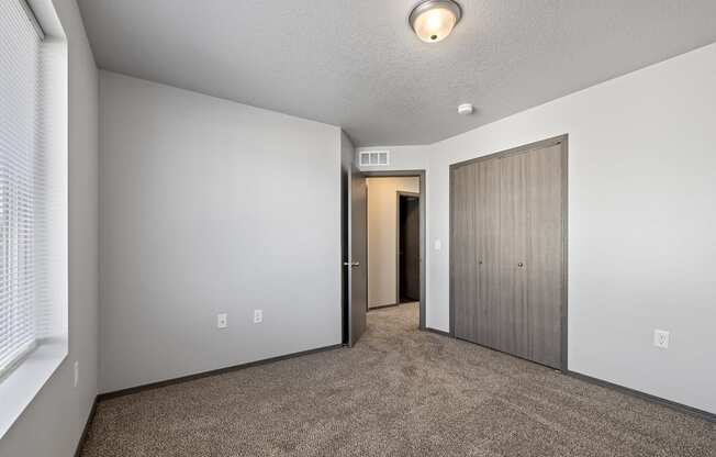 Bright, vacant bedroom with neutral walls and carpet flooring.