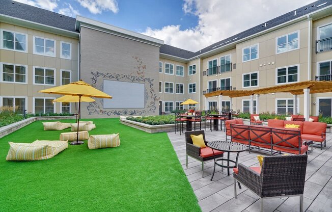 a courtyard with a lawn and tables and chairs