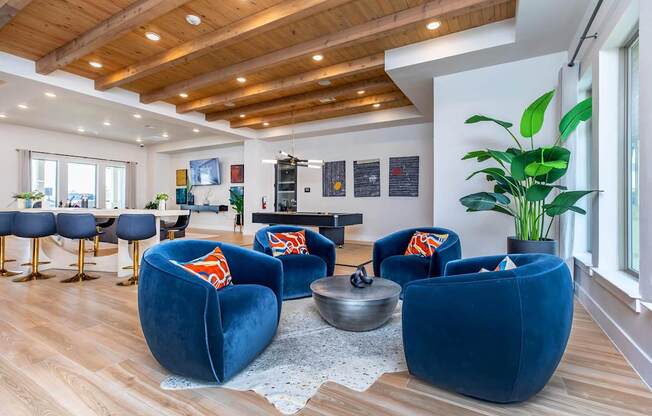 A living room with blue chairs and a wooden ceiling.