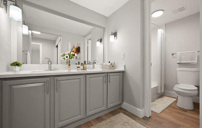 A bathroom with a white toilet and grey cabinets.