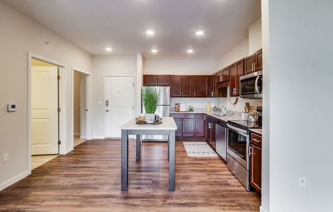 a kitchen with dark wood cabinets and stainless steel appliances and a white table with a plant on