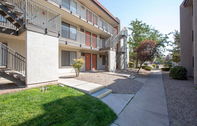 an exterior view of an apartment building with a sidewalk and grass