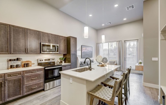 One bedroom model kitchen with island and wood-style flooring and view to living room