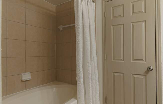 a bathroom with a tub and a shower and a white door