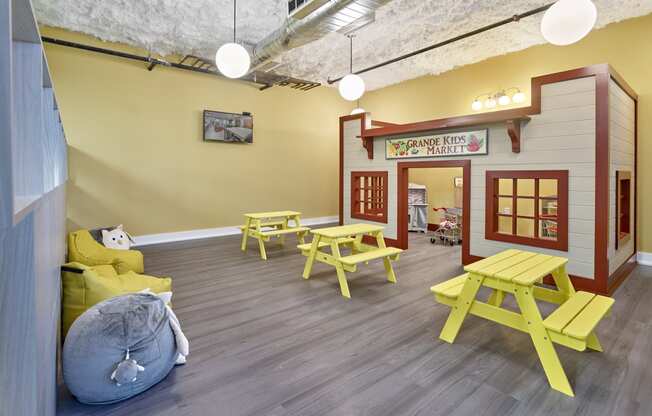 a play area with picnic tables and chairs and a play house