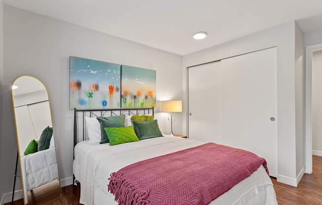 A bedroom with a large bed and a painting on the wall.