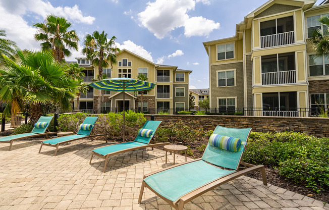 outdoor chairs and umbrellas in front of apartment buildings in pool area