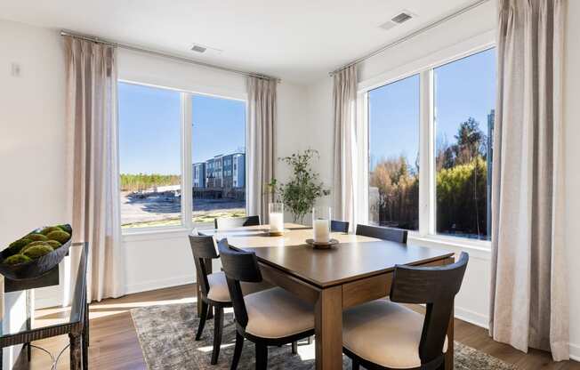 a dining room with large windows and a wooden table and chairs