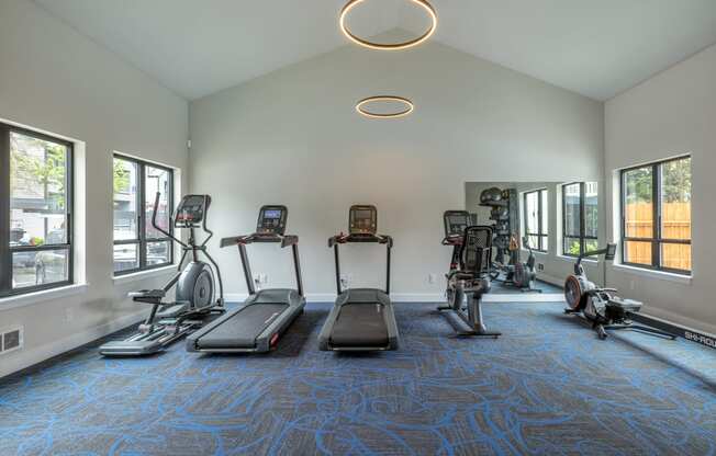 a gym with treadmills and other exercise equipment in a building with windows