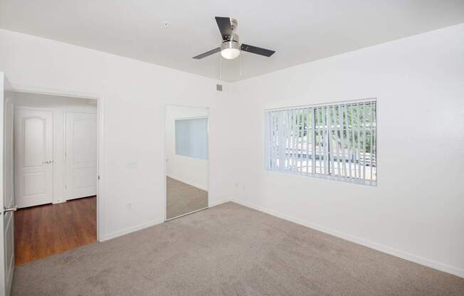 A room with a ceiling fan and a window with blinds.