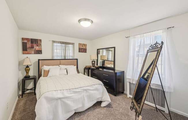 A bedroom with a large bed, a dresser, and a mirror.