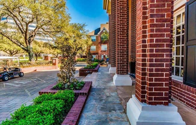 A brick building with a tree and a small garden in front.