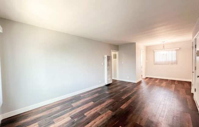 an empty living room with wood flooring and white walls