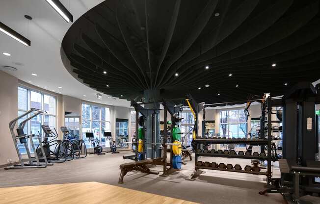 A gym with a variety of equipment including treadmills, weights, and exercise bikes.