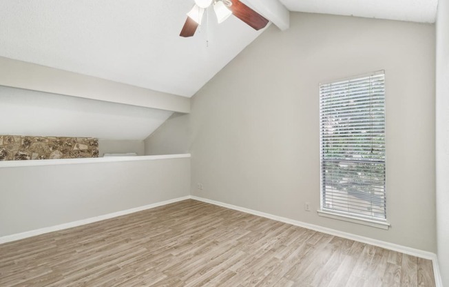 a bedroom with a large window and wood flooring