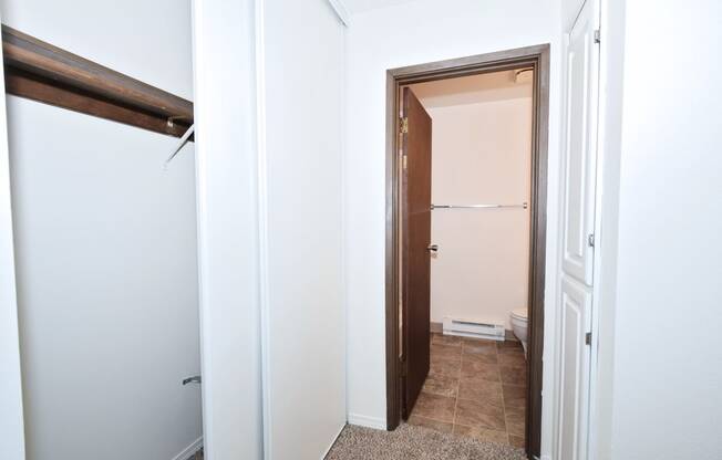 a walk in closet in a bedroom with white walls and a tiled floor