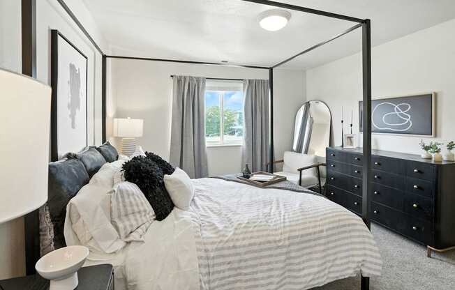 A bedroom with a large bed and a black dresser.