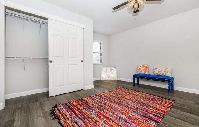 a living room with a ceiling fan and a colorful rug