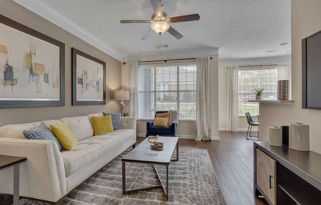 A living room with a white couch, a coffee table, and a ceiling fan.