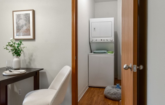 a small room with a washing machine and a desk and a chair