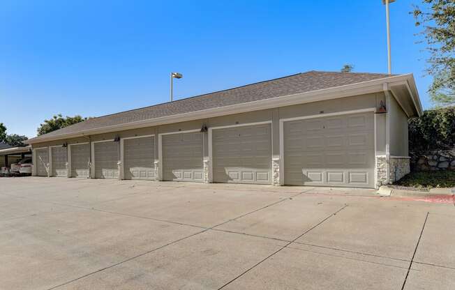 an empty parking lot in front of a building with garage doors