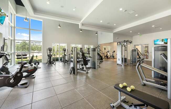 a gym with weights and cardio equipment in a building with windows