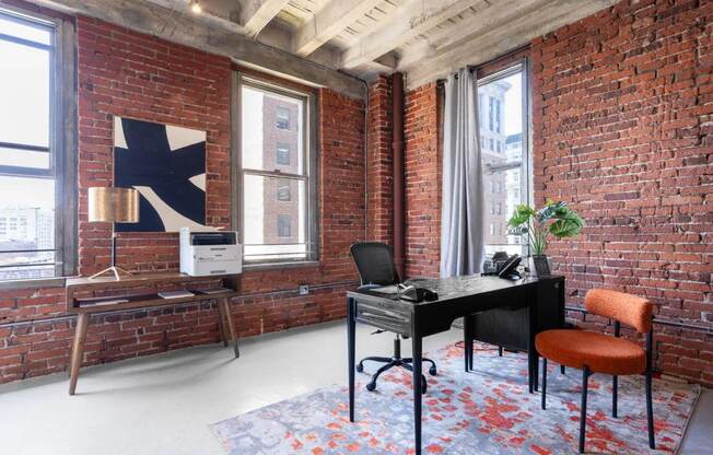 an exposed brick wall in a room with a desk and a chair