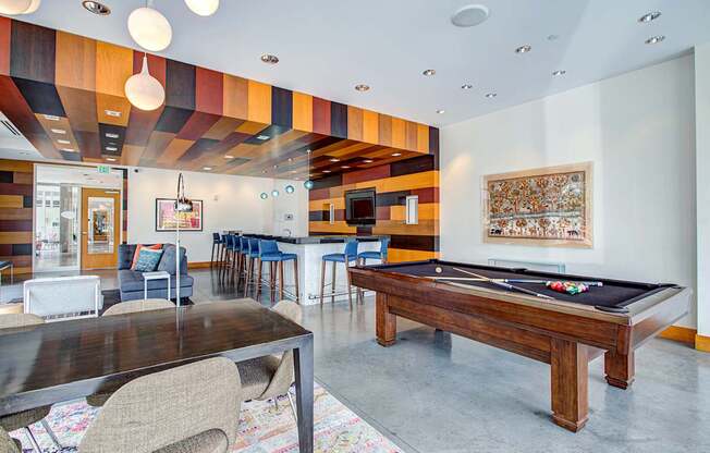 A room with a pool table and a bar area.