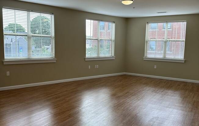 an empty room with three windows and a wooden floor