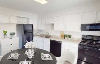 A kitchen with white cabinets and a black refrigerator.
