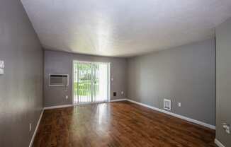 an empty living room with wood floors and a sliding glass door