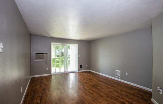 an empty living room with wood floors and a sliding glass door