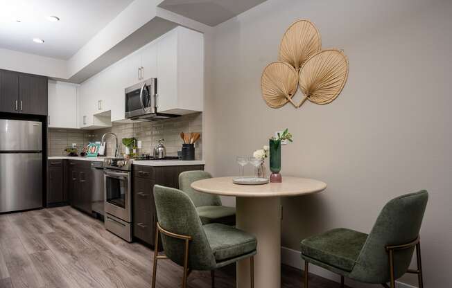 Apartments Near USC- Living Room With Open Floorplan, Kitchen View With Stainless-Steel Appliances, Wood-Style Floors, And Large Windows