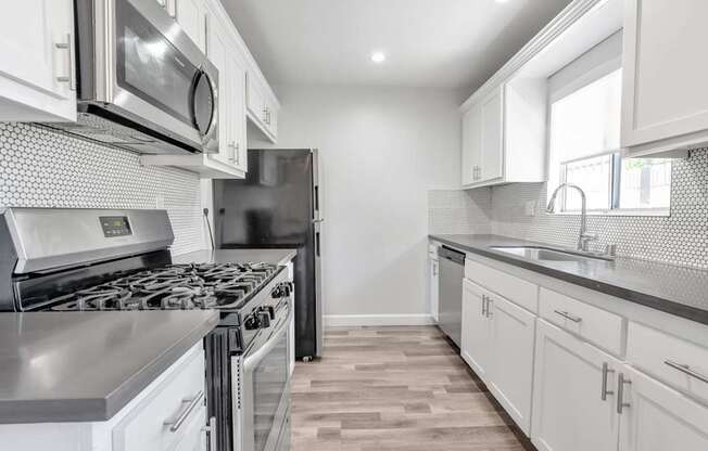 A modern kitchen with white cabinets and stainless steel appliances.