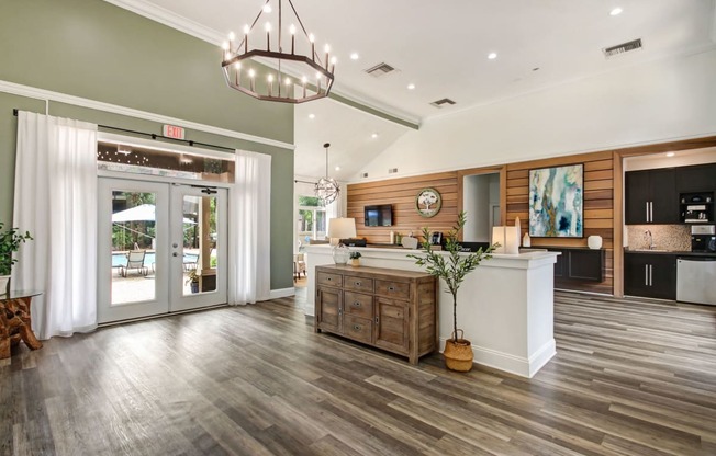 a living room with a kitchen and a chandelier