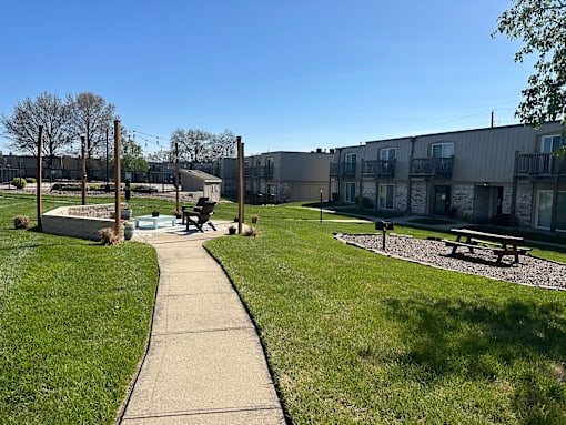 a walkway through a park with benches and buildings