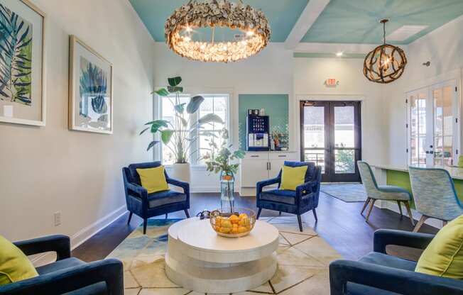 a living room with blue chairs and a round table and a chandelier