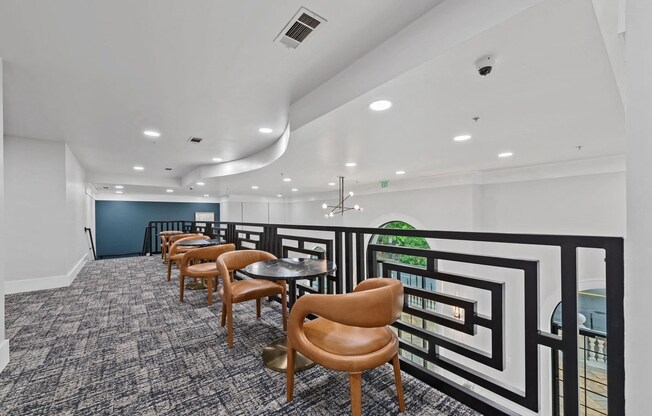 A series of chairs with cafe style tables on the upper level of a room.