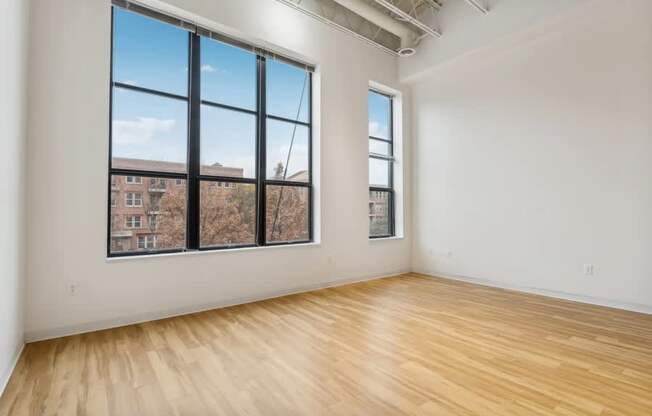 A room with wooden floors and large windows overlooking a cityscape.