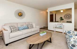 A living room with a couch, coffee table, and mirror at Sutton Hill Apartments, IOWA, 50320