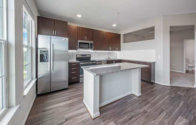 a kitchen with a large island and stainless steel refrigerator