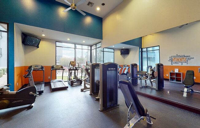 a gym with cardio equipment and a large window