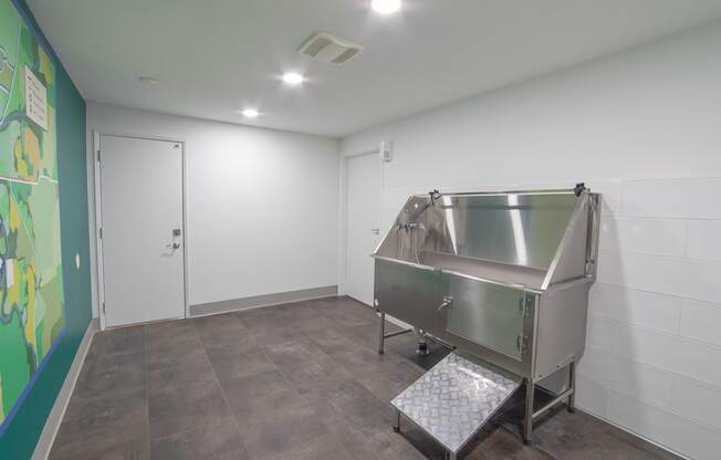 a large stainless steel tub sits in the corner of a room with a green mural on the