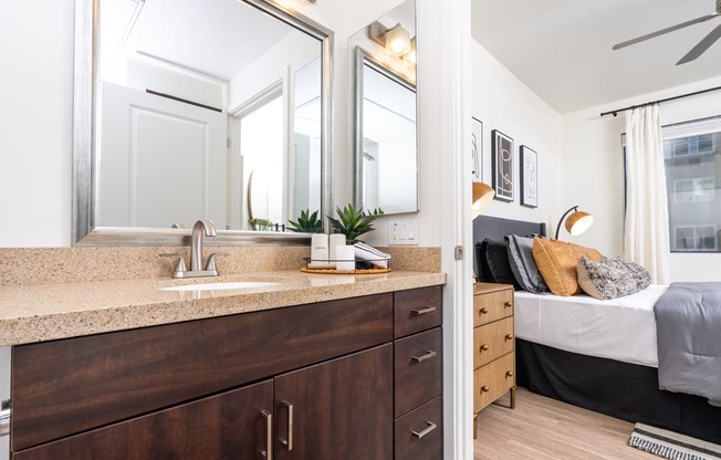 a bathroom with a sink and a mirror and a bedroom with a bed