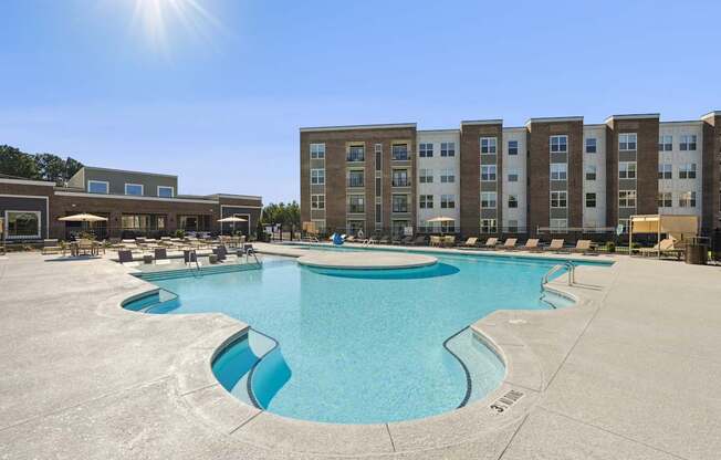 A large swimming pool in front of apartment buildings on a sunny day.