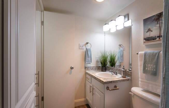 A bathroom with a white vanity in the 558 square foot 1 bedroom, 1 bath model apartment at The Summit at Midtown Apartments in the Dallas Midtown neighborhood of Dallas, TX.